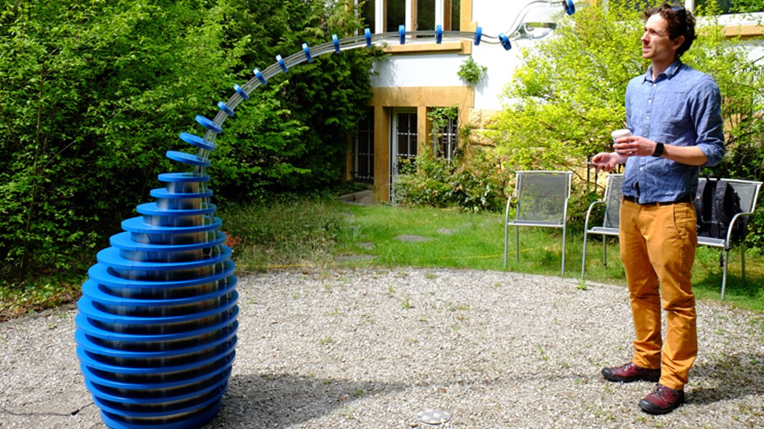 Der Sensor im Objekt nimmt eine Person in der nahen Umgebung wahr. Der Schlauch beugt sich langsam zur Person hin, die einen Becher in der Hand halten sollte. Die Karaffe am Ende des Schlauches neigt sich mit dem Gewicht des Wassers so weit, bis das Wasser aus dem Behälter im Objekt in den Becher der Person fliesst.  Der Sensor im Objekt nimmt eine Person in der nahen Umgebung wahr. Der Schlauch beugt sich langsam zur Person hin, die einen Becher in der Hand halten sollte. Die Karaffe am Ende des Schlauches neigt sich mit dem Gewicht des Wassers so weit, bis das Wasser aus dem Behälter im Objekt in den Becher der Person fliesst.