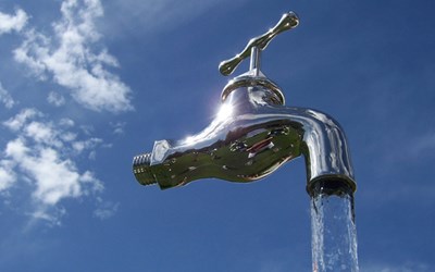 Eine Pumpe bringt Wasser in einer Plexiglasröhre zum Wasserhahn hinauf, Wasser fliesst ausserhalb der Plexiglasröhre in einen Behälter hinunter.  Eine Pumpe bringt Wasser in einer Plexiglasröhre zum Wasserhahn hinauf, Wasser fliesst ausserhalb der Plexiglasröhre in einen Behälter hinunter.